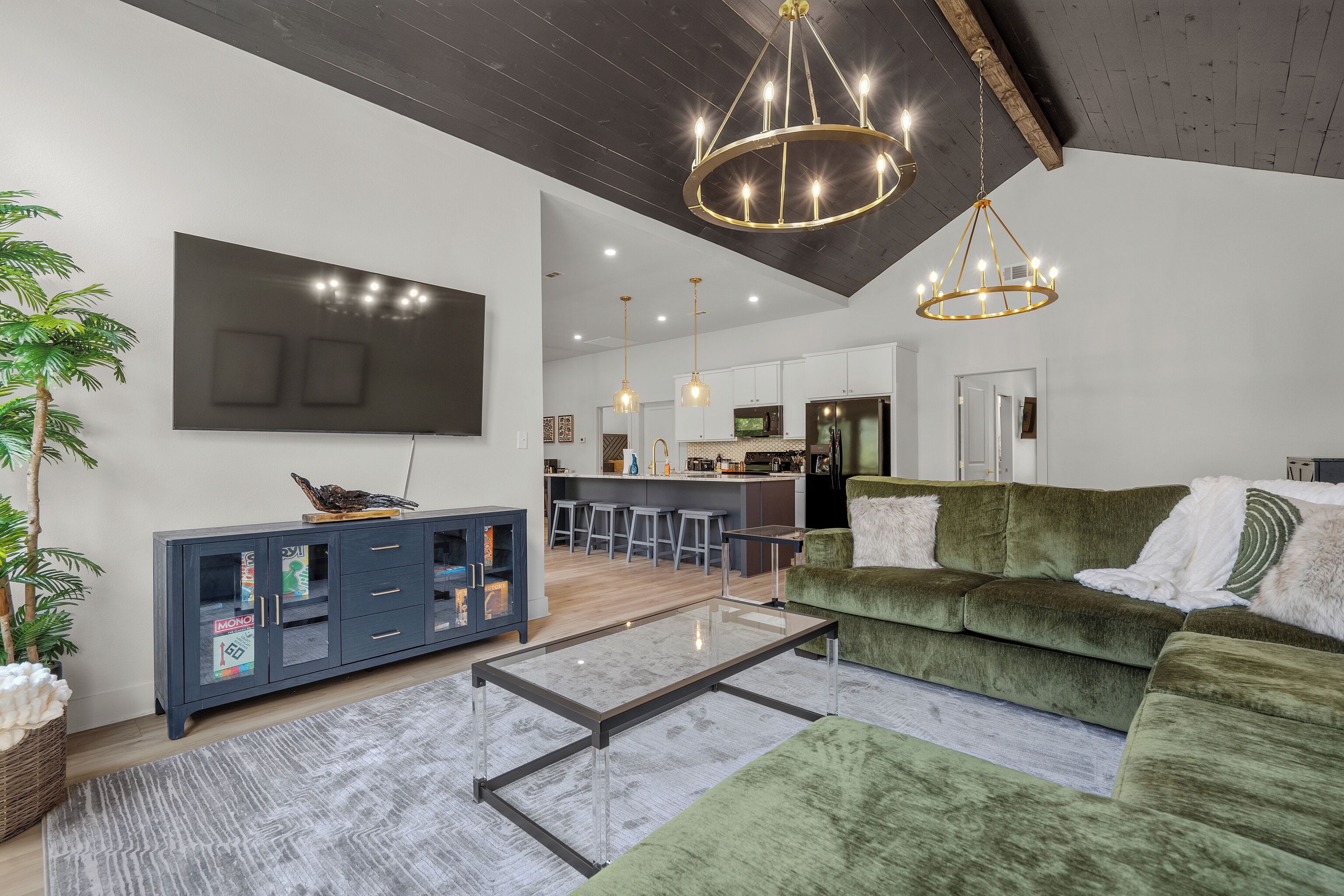 A modern living room with a green sofa, a coffee table, and a TV mounted on the wall.