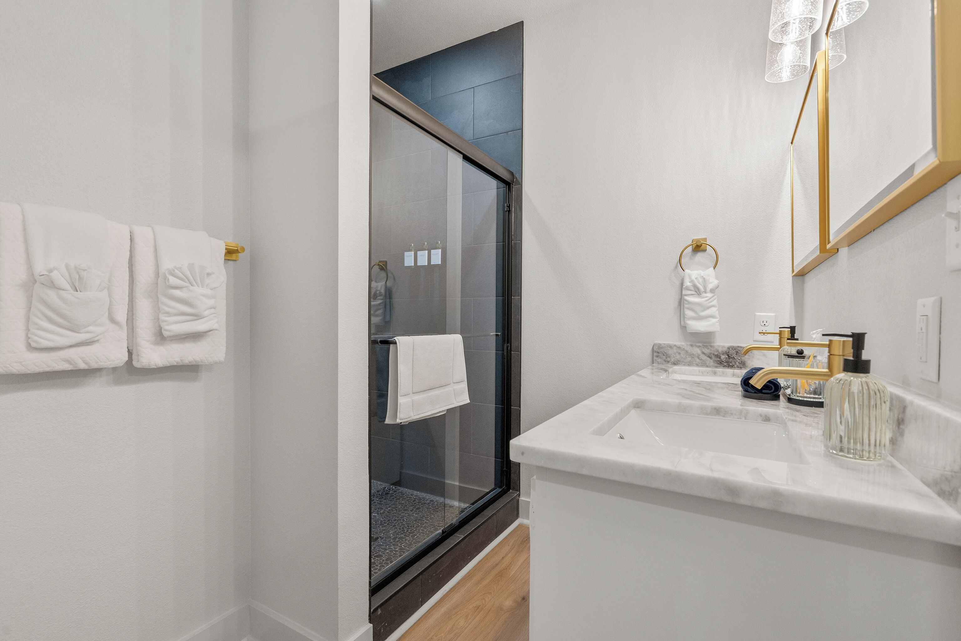 A modern bathroom with a glass shower enclosure, a marble sink, and neatly arranged towels.