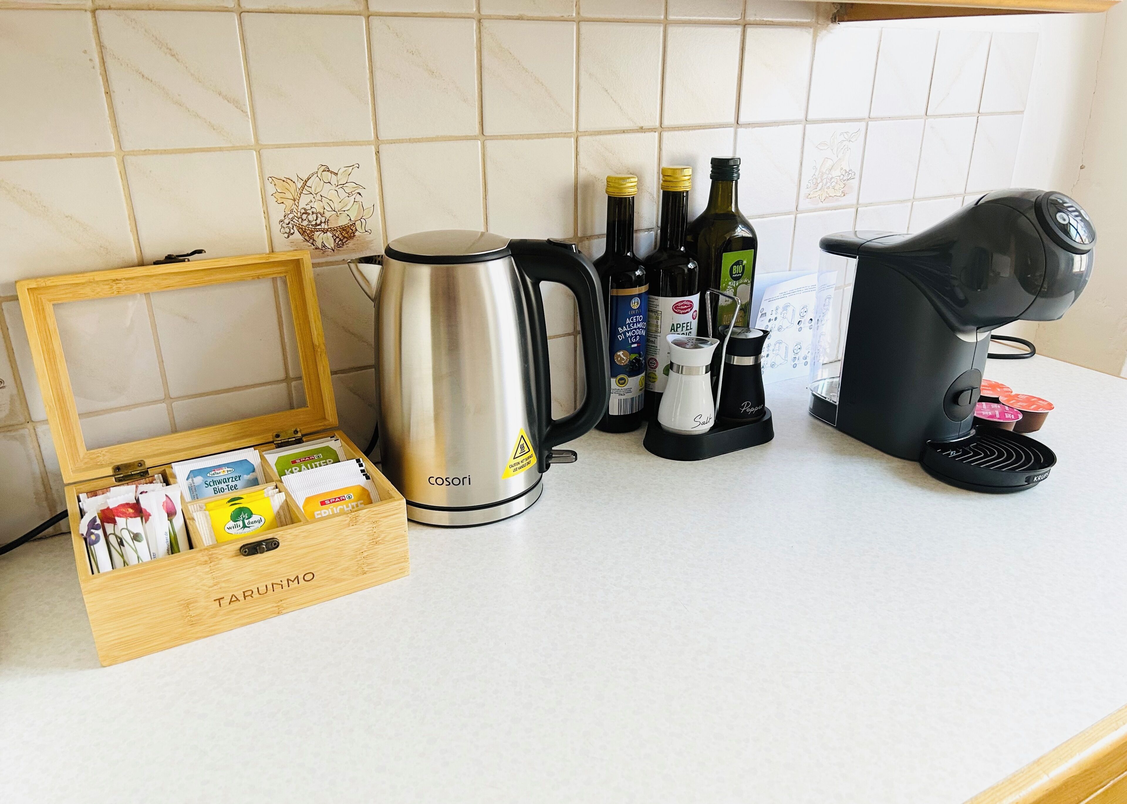 Eine Küchenarbeitsplatte mit Kaffeemaschine, Wasserkocher und einer Packung Teebeuteln.