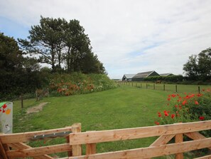 A rural landscape with a wooden fence, a barn, and a horse in the distance. - 6-guest Texel Villa With Sauna & Spa (De Koog)