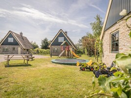 Ein Wohngebiet mit zwei Häusern, einem Spielplatz, einem Trampolin und einem Picknicktisch.