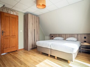 A bedroom with a bed, wooden wardrobe, and a hanging light fixture. - 6-guest Texel Villa With Sauna & Spa (De Koog)