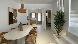 A modern interior with a dining area, kitchen, and staircase. - Borgo Stampalia – Villa Terracotta (Astypalea)