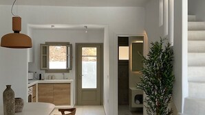 A modern kitchen with a dining area, a staircase, and a potted plant. - Borgo Stampalia – Villa Terracotta (Astypalea)