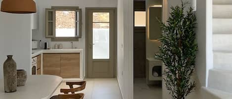 A modern kitchen with a dining area, a staircase, and a potted plant.