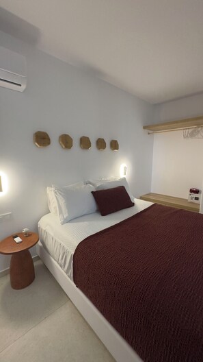 Ein Schlafzimmer mit Bett, Nachttisch, Wandleuchte und einer kleinen Ablage.