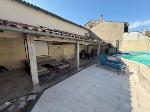 A covered outdoor area with a pool, lounge chairs, a table, and a seating area. - House in the city center near a public park and the banks of the Charente River (Cognac)
