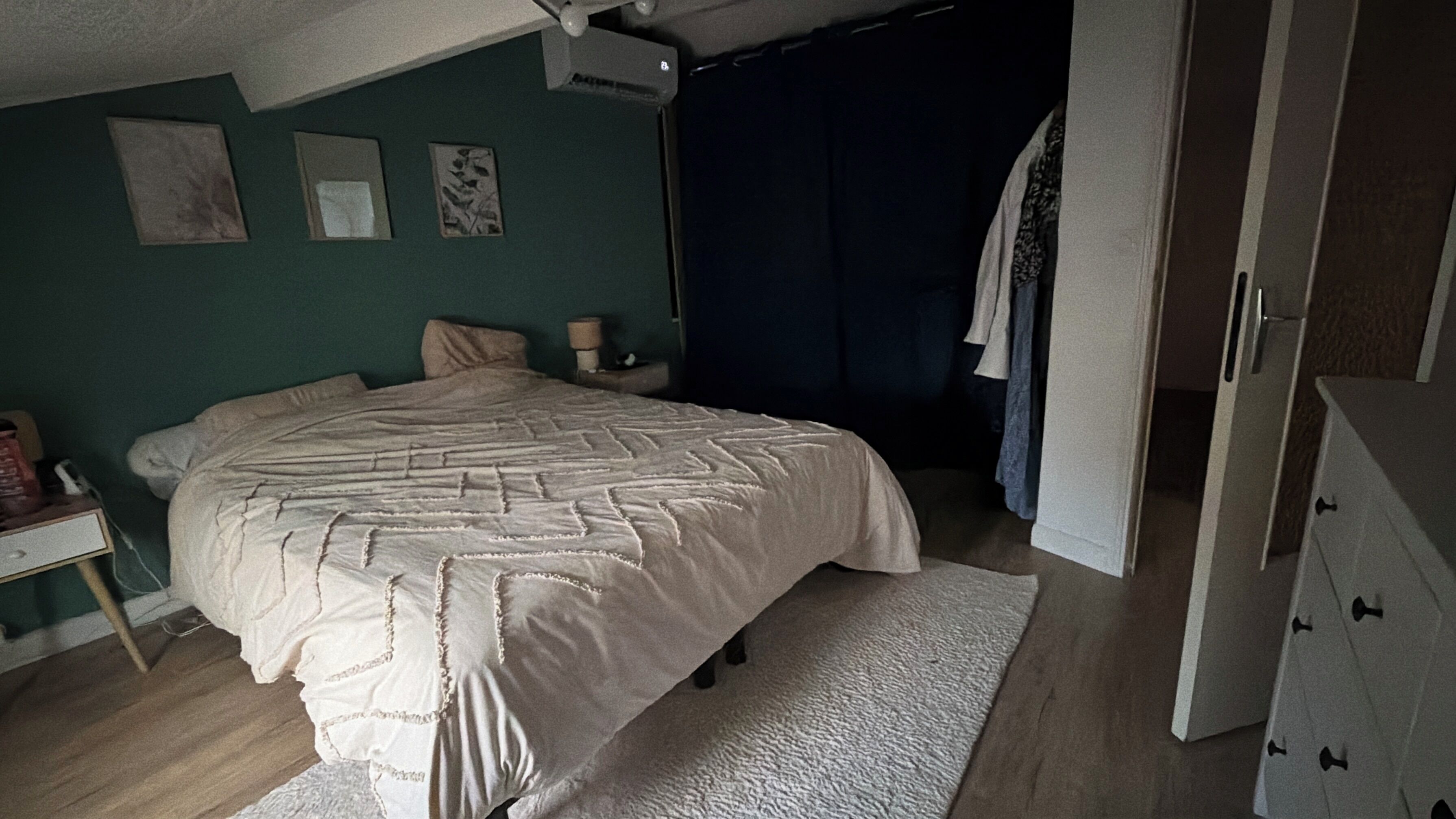 Une chambre à coucher avec un lit, une commode, une table de chevet et une fenêtre avec des rideaux.