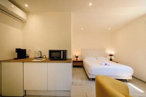 Une chambre d’hôtel compacte comprenant un coin cuisine, un lit et un petit espace salon.