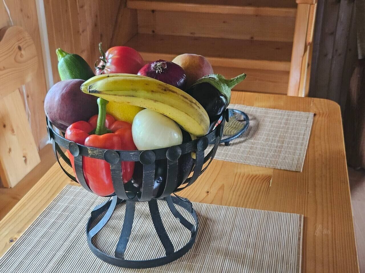 En skål med frugt på et træbord med en vævet bordskåner.