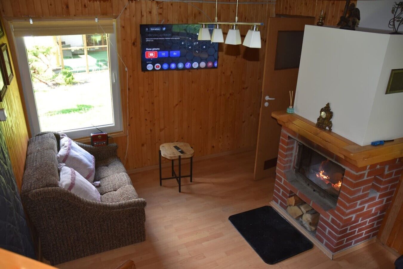 Una sala de estar acogedora con chimenea, un televisor montado en la pared y un ventanal con vistas al exterior.