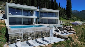 A modern two-story house with a swimming pool, stone steps, and a garden with rocks and plants. - Vrbo Property (Lombardia)