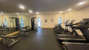 A gym with various exercise equipment including treadmills, a stationary bike, and weight machines. - Mexican Designer Studio - Pool, Gym, and Rooftop (Ciudad de México)