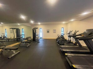 A gym with various exercise equipment including treadmills, a stationary bike, and weight machines. - Mexican Designer Studio - Pool, Gym, and Rooftop (Ciudad de México)
