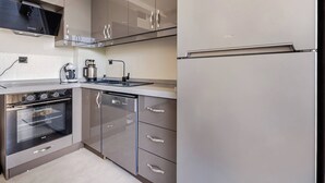 Moderni keittiö, jossa on ruostumattomasta teräksestä valmistetut kodinkoneet, sisäänrakennettu uuni ja jääkaappi.
