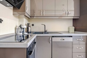 Eine moderne Küche mit Einbauofen, Geschirrspüler und Kaffeemaschine.