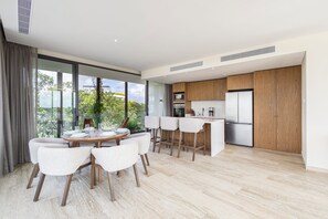 Een moderne keuken met houten kastjes, een centraal eiland en een eethoek met witte stoelen.