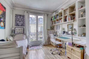 Ein helles Zimmer mit einem Bett, einem Schreibtisch und einem Bücherregal.