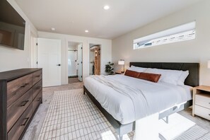 Une chambre à coucher comprenant un lit, des tables de chevet, une commode, un miroir et un placard.