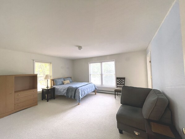 Un dormitorio con cama, cómoda, silla y ventana.