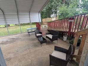 An outdoor patio with wicker furniture, a covered area, and a wooden deck.
