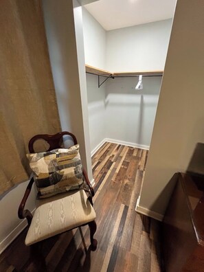Une petite pièce fermée, dotée d’un plancher en bois, d’un banc avec des coussins et d’une étagère fixée au mur.