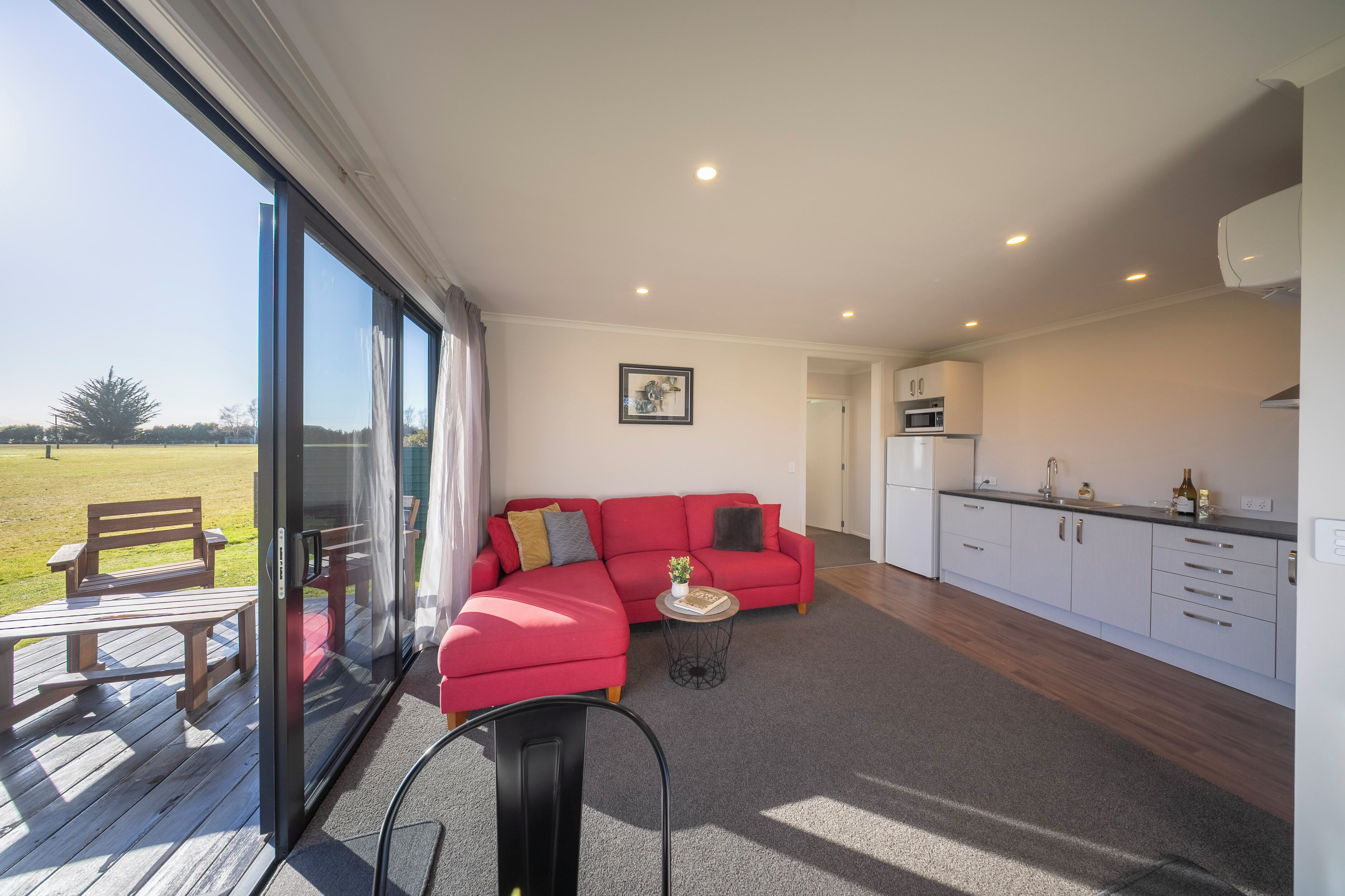 A modern living room with a red sectional sofa, a small round table, and a glass door leading to an outdoor area.