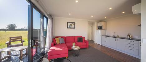 A modern living room with a red sectional sofa, a small round table, and a glass door leading to an outdoor area.