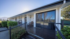 En modern byggnad med ett takförsett utomhusområde, trästeg och ett räcke.