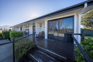 Ein modernes Gebäude mit überdachter Außenbereich, Holzstufen und Geländer.
