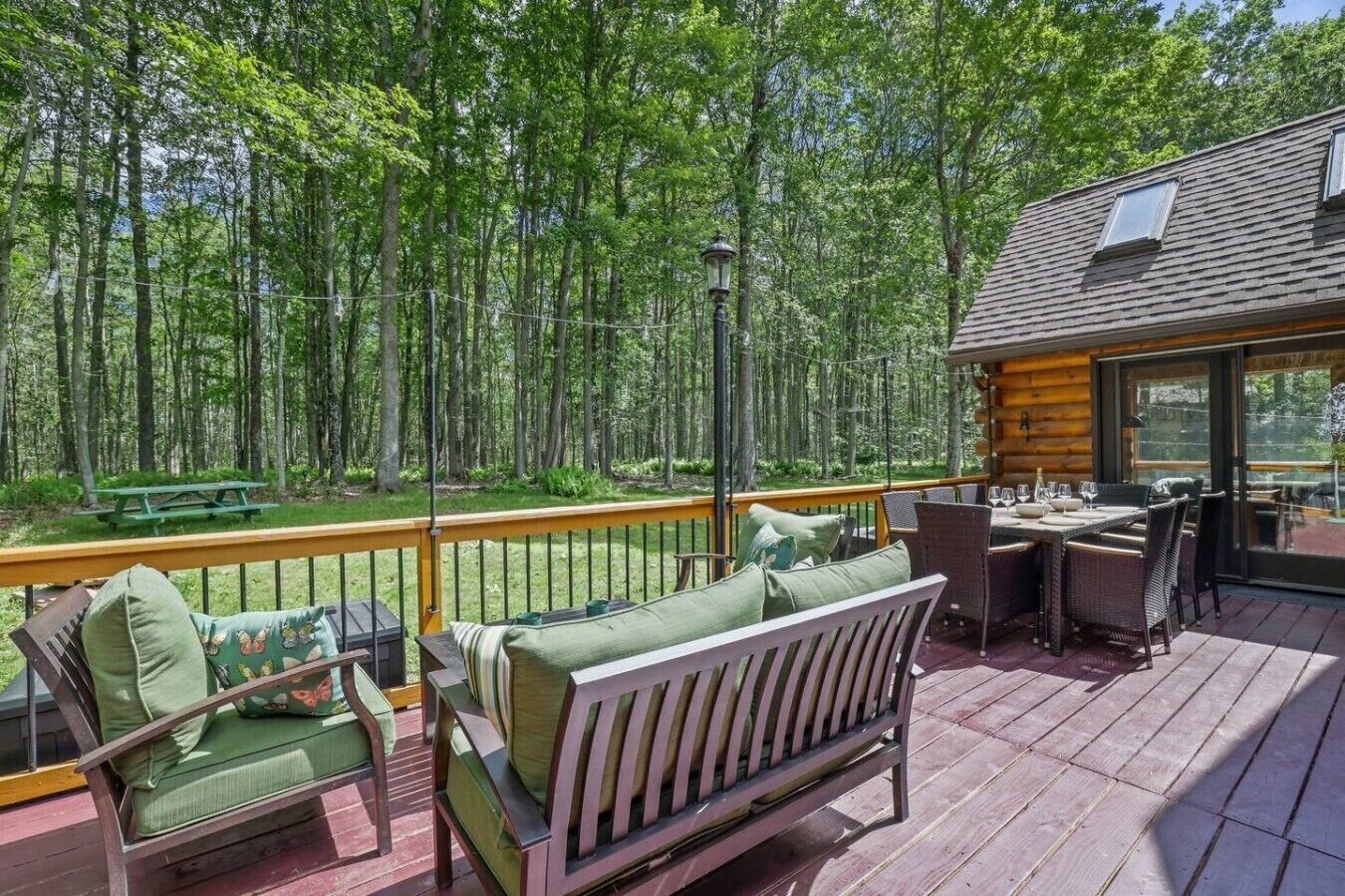 Eine Terrasse mit Gartenmöbeln, einem Essbereich und Blick auf einen Wald.