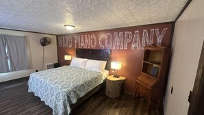 A hotel room with a bed, two bedside lamps, a nightstand, a wooden dresser, and a ceiling fan. - Ward Loft 2 (Fireplace, King Bed, Smart TV) (Canton)