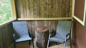 A wooden deck with two chairs and a tree stump table. - Ward Loft 2 (Fireplace, King Bed, Smart TV) (Canton)