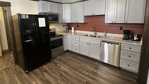 A modern kitchen with white cabinets, stainless steel appliances, and a wooden floor. - Ward Loft 2 (Fireplace, King Bed, Smart TV) (Canton)