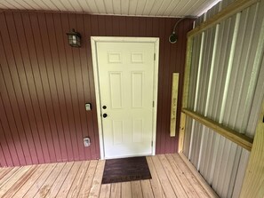 A white door with a doorknob and a doorbell, a wooden door frame, a metal door frame, and a welcome mat. - Ward Loft 2 (Fireplace, King Bed, Smart TV) (Canton)