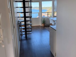 Una cocina moderna con vistas al mar, piso de madera y un estante metálico negro.