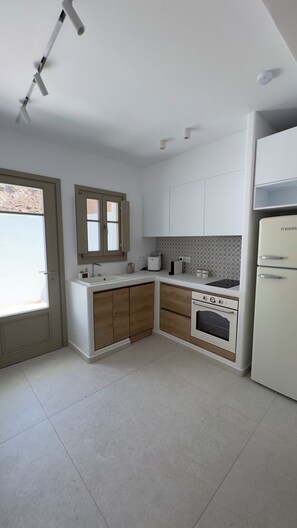 A kitchen with white cabinets, a built-in oven, and a refrigerator. - Borgo Stampalia – Villa Sabbia (Astypalea)