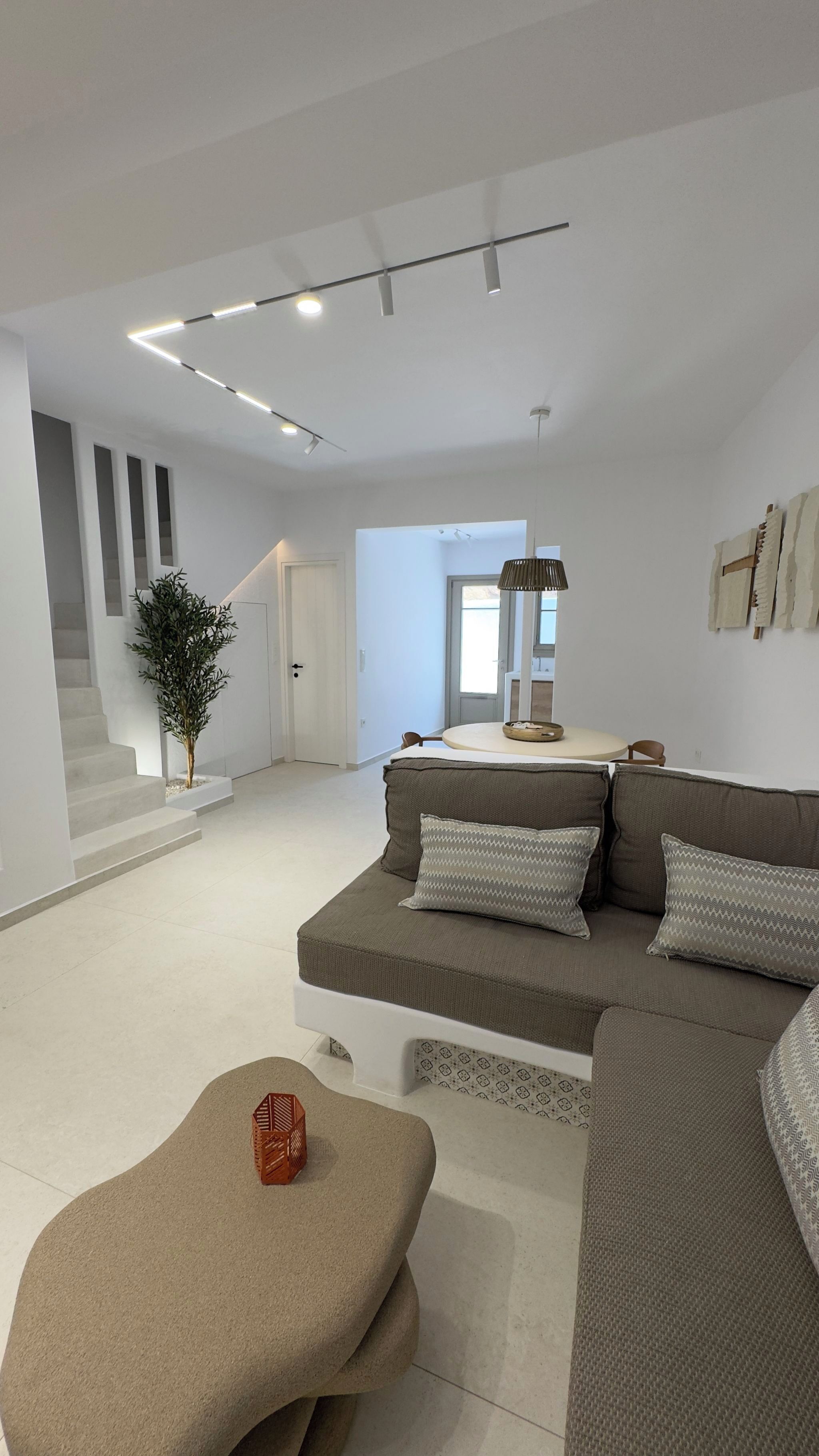 Un salon moderne avec un canapé d’angle, une table basse et un escalier menant à une autre pièce.