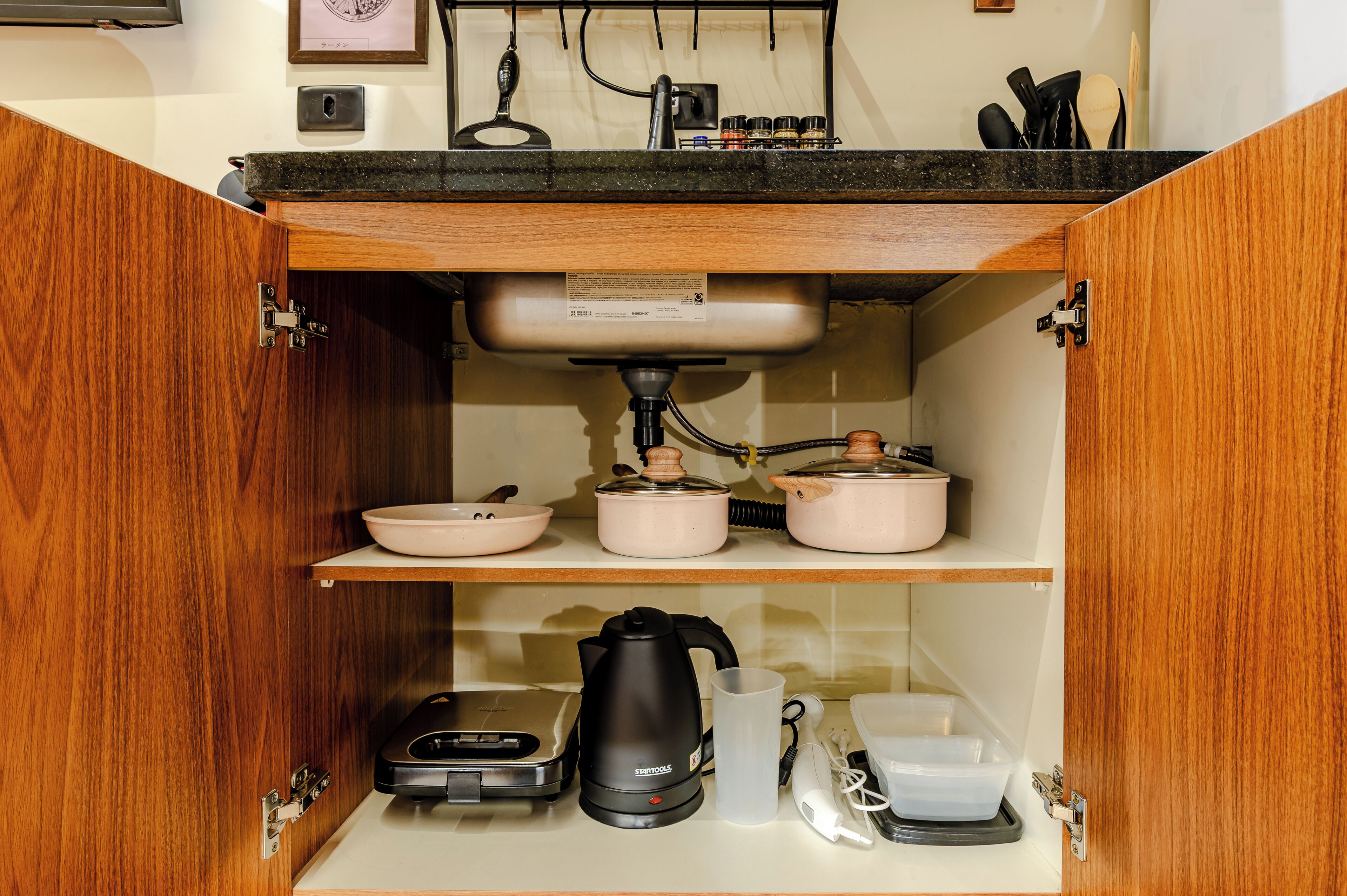 A kitchen with a built-in sink, a coffee maker, a kettle, and a rice cooker on the countertop.