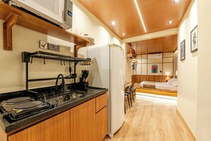 A compact kitchen with a stove, sink, and a refrigerator. - TOKA Urban Stay (São Paulo)