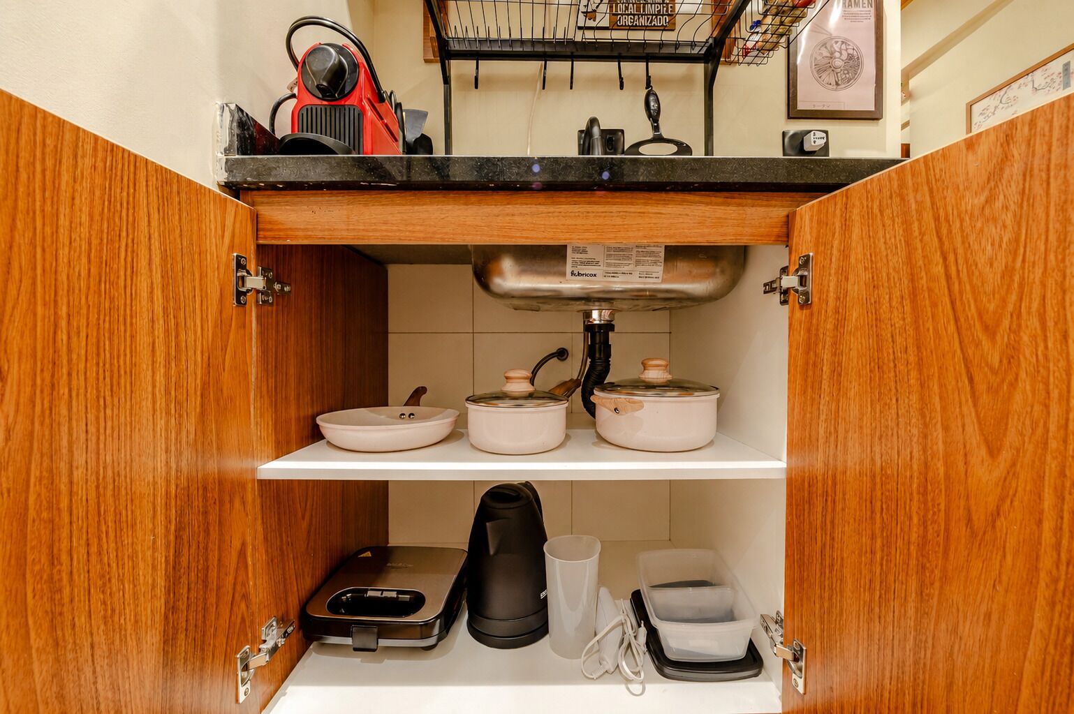 A kitchen with wooden cabinets, a sink, and various kitchen appliances including a kettle, pots, and a coffee maker.