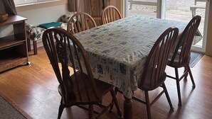 A dining area with a table covered in a patterned tablecloth, surrounded by wooden chairs. - 3-bedroom Waterview cabin with AC in charming Birchwood (Birchwood)