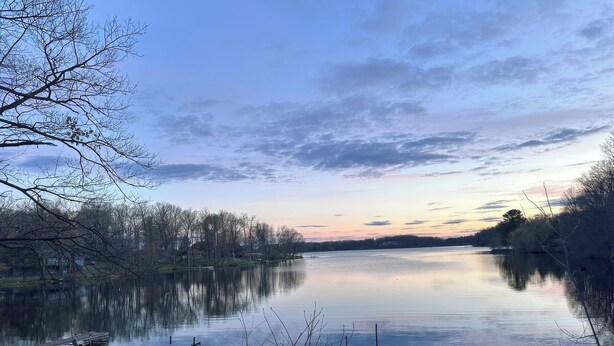 A calm lake with a wooden dock and a bridge leading to a small island. - 3-bedroom Waterview cabin with AC in charming Birchwood | Waterview Cabin with Private Boat Slip (Birchwood)