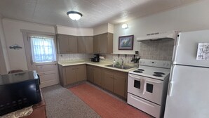 A compact kitchen with a stove, refrigerator, and sink. - 3-bedroom Waterview cabin with AC in charming Birchwood (Birchwood)