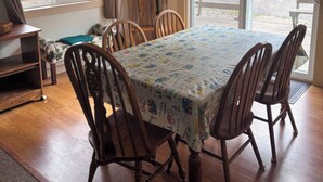 A dining area with a table covered in a patterned tablecloth, surrounded by wooden chairs. - 3-bedroom Waterview cabin with AC in charming Birchwood | Waterview Cabin with Private Boat Slip (Birchwood)