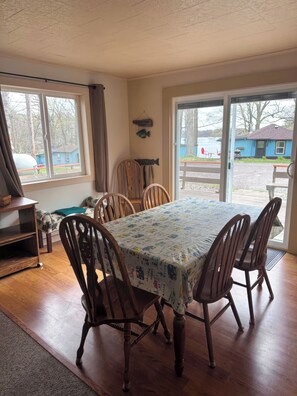 A dining area with a table covered in a patterned tablecloth, surrounded by wooden chairs. - 3-bedroom Waterview cabin with AC in charming Birchwood | Waterview Cabin with Private Boat Slip (Birchwood)