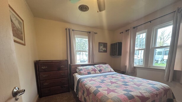 A bedroom with a bed, dresser, and windows. - 3-bedroom Waterview cabin with AC in charming Birchwood (Birchwood)