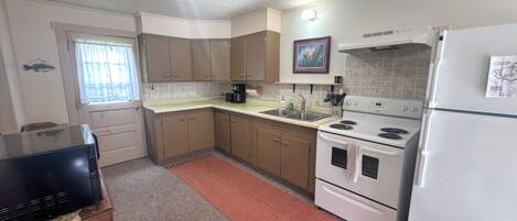 A kitchen with a refrigerator, stove, sink, and cabinets.