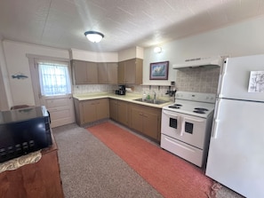 A kitchen with a refrigerator, stove, sink, and cabinets. - 3-bedroom Waterview cabin with AC in charming Birchwood | Waterview Cabin with Private Boat Slip (Birchwood)