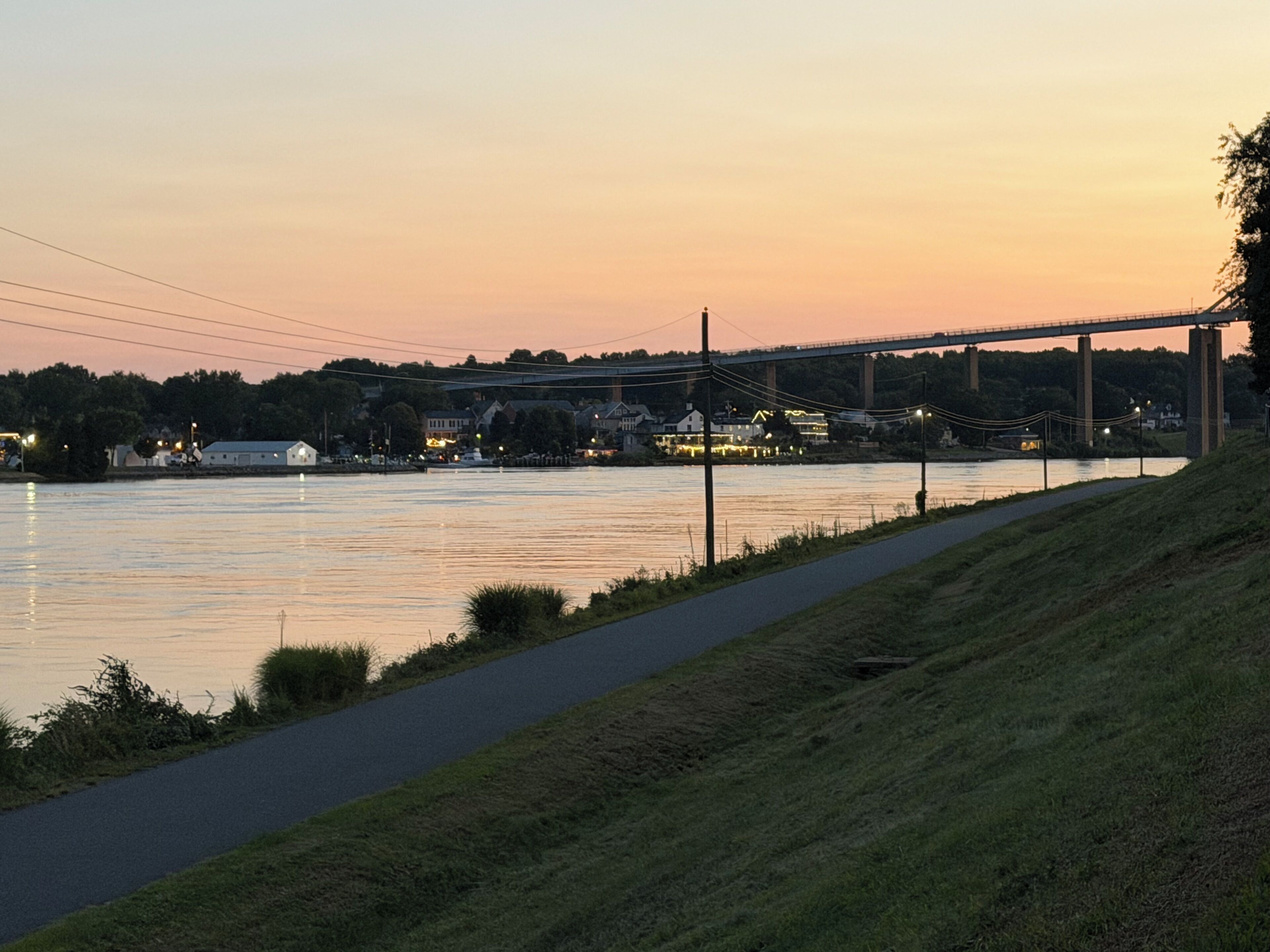 A riverside walkway with a bridge in the background.